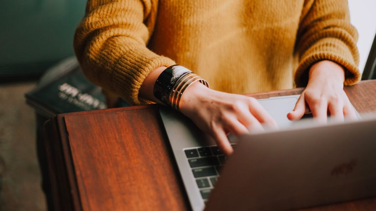 close up of womans hands typing on laptop