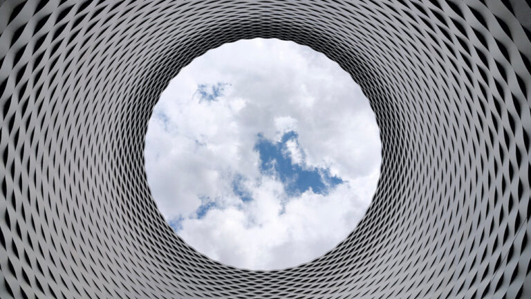 looking up through circular building and seeing clouds