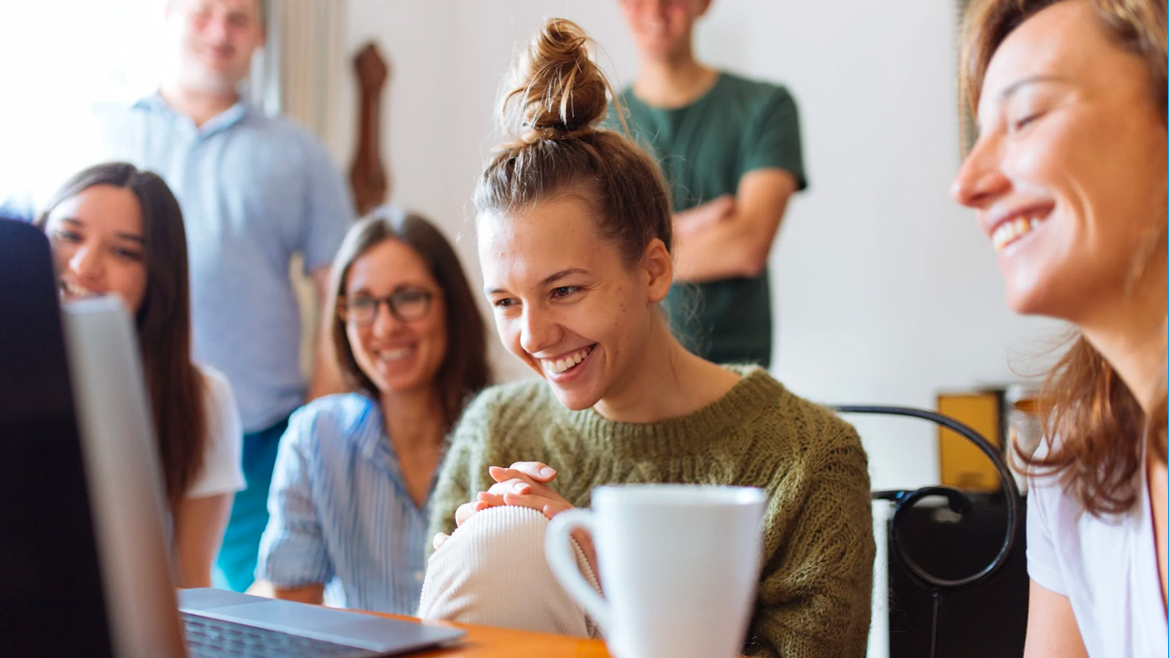 group of people smiling and starring at laptop