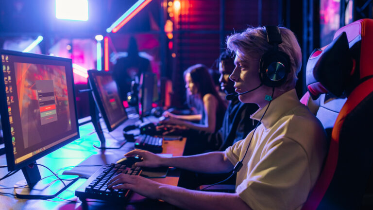young men and women gaming in a dark neon lite room