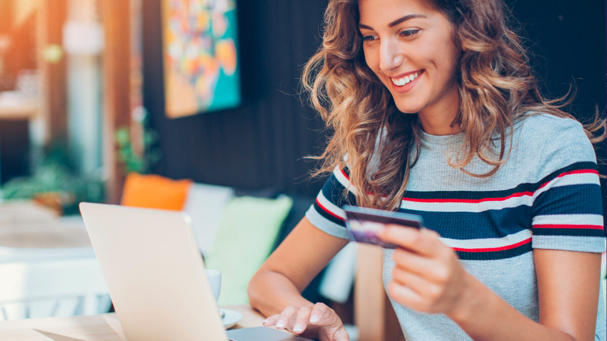 woman smiling while paying for something on her laptop using her credit card