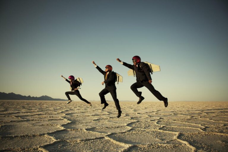 Businessmen taking flight in the desert with jet packs